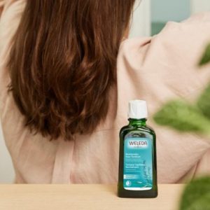Woman applying Weleda Revitalising Hair tonic with rosemary