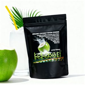 Organic coconut water powder in black pouch with a green coconut cut on the side with coocnut water in a tall glass made from cocontu water powder